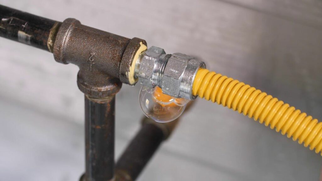 A gas leak detector attached to a yellow gas line, with bubbles forming, indicating a leak.